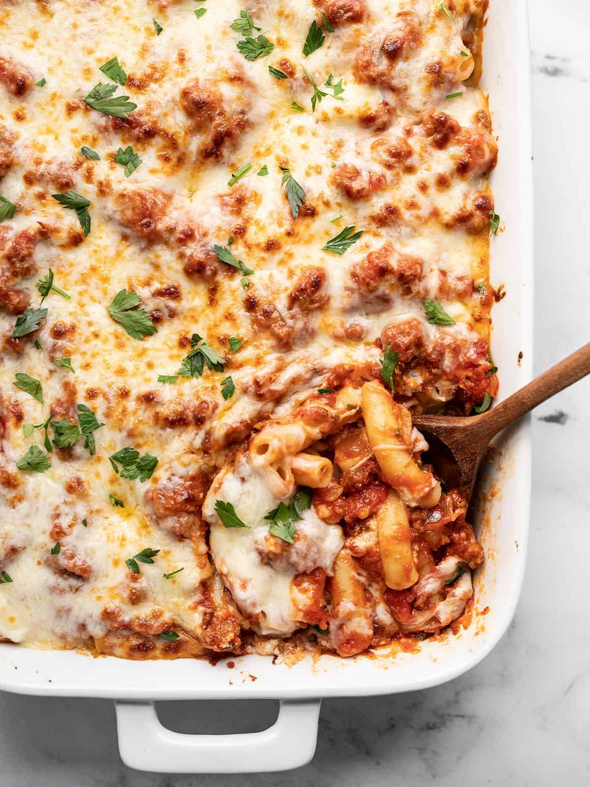 Like a freeform lasagna, this Baked Ziti has layers of pasta, homemade red sauce with Italian sausage, and three types of melty cheese! BudgetBytes.com Overhead view of a casserole dish full of baked ziti with the corner being scooped out.